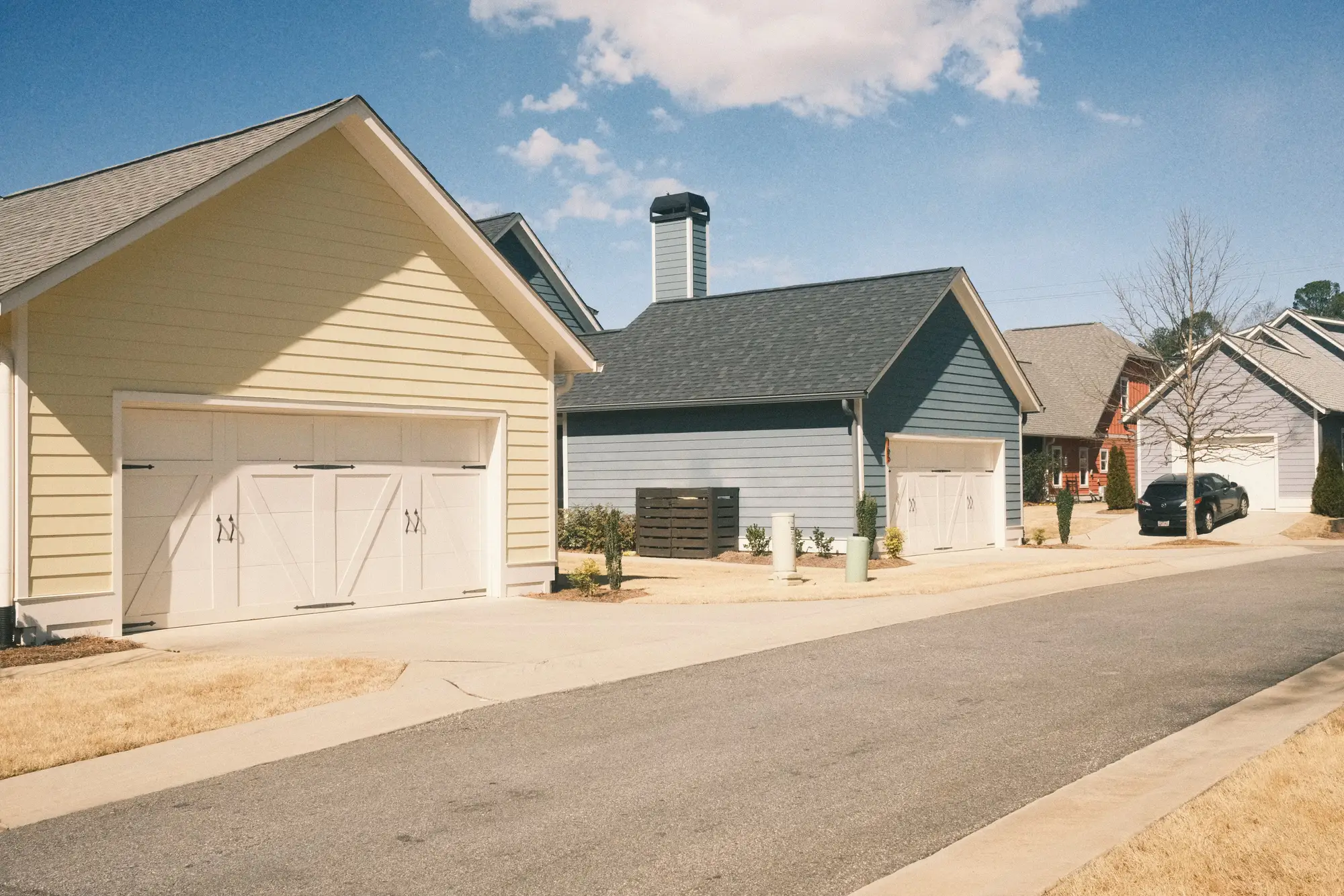 A row of new detached garages with concrete driveways on a suburban street